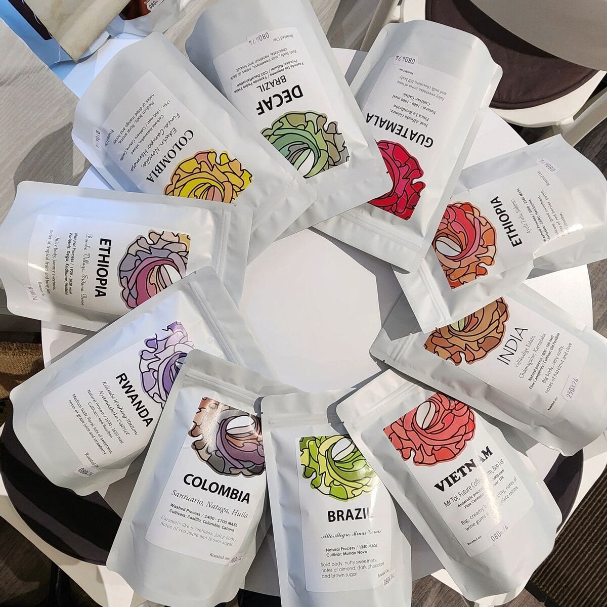 A circle of white Cafe Moly coffee bags with illustrated labels.